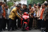 Presiden Joko Widodo (tengah) mendengarkan penjelasan dari Menristekdikti M Nasir (kelima kiri) sebelum menjajal motor listrik buatan dalam negeri 'Gesits' seusai melakukan audiensi dengan pihak-pihak yang terlibat proses produksi di halaman tengah Istana Kepresidenan, Jakarta, Rabu (7/11/2018). Audiensi tersebut membahas persiapan produksi massal sepeda motor listrik Gesits. Antara Foto/Wahyu Putro A