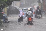 Pengguna jalan berusaha melintasi genangan banjir di jalan Gajayana, Malang, Jawa Timur, Senin (10/12/2018). Hujan deras yang melanda kawasan tersebut mengakibatkan banjir di sejumlah titik.  Antara Jatim/HO/H Prabowo/ZK.