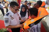 Direktur SDM dan Umum PT Pelayaran Nasional Indonesia (Persero) Ganefi (kedua kiri) memakaikan jaket pelampung kepada pelaku pelayaran rakyat (Pelra) di Terminal Jamrud Selatan, Pelabuhan Tanjung Perak, Surabaya, Jawa Timur, Kamis (20/12/2018). Pemberian sebanyak 250 jaket pelampung kepada pelaku pelayaran rakyat tersebut merupakan bentuk tanggung jawab sosial PT Pelni (Persero) sekaligus dalam rangka menciptakan keselamatan angkutan kapal menjelang Natal dan Tahun Baru. Antara Jatim/Moch Asim/ZK.