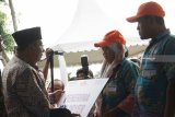 Menko Perekonomian Darmin Nasution (kiri) menyerahkan bantuan Program Padat Karya Tunai (PKT) dari PT Bank Negara Indonesia (Persero) Tbk (BNI) kepada warga secara simbolis di sela-sela acara Tanam Padi Massal di Desa Ternyang, Sumberpucung, Malang, Jawa Timur, Kamis (13/12/2018). Bantuan tersebut merupakan bentuk komitmen dan dukungan BNI terhadap Gerakan Mengawal Musim Tanam Oktobr 2018-Maret 2019 untuk meningkatkan produktivitas dan kesejahteraan para petani. Antara Jatim/HO/Orin Basuki/ZK.