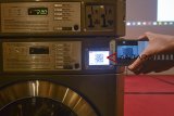 Seorang pekerja mencoba aplikasi metode pembayaran laundry digital di Bandung, Jawa Barat, Sabtu (15/12/2018). LG electronics menggandeng PT. Triton Internasional Indonesia untuk mengenalkan konsep terbaru mesin cuci laundry digital dengan metode pembayaran menggunakan kartu khusus, dan aplikasi di smartphone. ANTARA JABAR/Raisan Al Farisi/agr. 