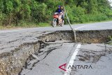 Pengguna jalan melintasi jalan lintas Aceh Tengah – Gayo Lues yang longsor di Kecamatan Bintang, Aceh Tengah, Aceh, Kamis (29/11/2018). Kondisi jalan yang amblas tersebut dapat mengancam keselamatan pengguna jalan karena kawasan tersebut sering diselimuti kabut saat malam hari. (Antara Aceh/Syifa Yulinnas)