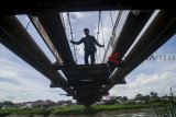 Warga menyeberangi Sungai Citarum menggunakan jembatan gantung yang rusak di Rancamanyar, Kabupaten Bandung, Jawa Barat, Minggu (30/12/2018). Jembatan penghubung antar kecamatan tersebut rusak setelah jadi akses utama sepeda motor saat banjir merendam jalan raya beberapa hari lalu. ANTARA JABAR/Raisan Al Farisi/agr. 