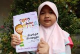 Siswa Kelas III SD Muhammadiyah Pontianak, Keisha Amelia Karenina (8 tahun) memperlihatkan novel Starlight Strianggle yang ditulis olehnya saat peluncuran di Balai Pelestarian Nilai Budaya Kalbar di Pontianak, Sabtu (15/12/2018). Novel tersebut bercerita tentang persahabatan sepuluh anak yang bersekolah di asrama dan berjuang bersama meraih impian untuk menjadi grup penyanyi terkenal hingga ke mancanegara. ANTARA FOTO/Jessica Helena Wuysang