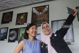 Anggota komunitas Malang Female Motret (MFM) melakukan swafoto di depan karyanya saat Pameran Fotografi Hari Ibu di  Arbanat Lounge, Malang, Jawa Timur, Sabtu (22/12/2018). Pameran yang berlangsung selama tiga hari tersebut menampilkan 24 hasil karya foto para perempuan dari berbagai profesi namun memiliki ketrampilan di bidang fotografi. Antara Jatim/Ari Bowo Sucipto/ZK.