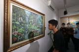 Pengunjung mengamati lukisan yang dipajang pada pameran seni rupa bertema Pesona Indonesia di galeri Prabangkara, Taman Budaya Jawa Timur, Surabaya, Jawa Timur, Selasa (4/12/2018). Sebanyak 20 lukisan karya sejumlah perupa Jawa Timur dipamerkan sampai 8 Desember 2018. Antara Jatim/Didik Suhartono/ZK.