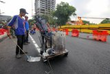 Pekerja membuat marka jalan di lokasi jalan ambles yang diaspal di Jalan Raya Gubeng, Surabaya, Jawa Timur, Kamis (27/12/2018). Proses perbaikan untuk memulihkan jalan ambles yang terjadi pada Selasa (18/12) lalu terus dilakukan agar dapat digunakan lagi bagi pengguna jalan. Antara Jatim/Didik Suhartono/ZK.