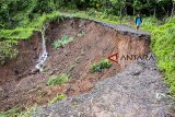 Warga berjalan melewati pinggiran jalan yang longsor di Desa Mekarjaya, Ciemas, Kabupaten Sukabumi, Jawa Barat, Sabtu (15/12/2018). Hujan deras yang melanda daerah itu menyebabkan akses jalan antar desa terputus akibat longsor menggerus badan jalan sepanjang 20 meter. ANTARA JABAR/Nurul Ramadhan/agr. 