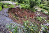 Warga berjalan melewati pinggiran jalan yang longsor di Desa Mekarjaya, Ciemas, Kabupaten Sukabumi, Jawa Barat, Sabtu (15/12/2018). Hujan deras yang melanda daerah itu menyebabkan akses jalan antar desa terputus akibat longsor menggerus badan jalan sepanjang 20 meter. ANTARA JABAR/Nurul Ramadhan/agr. 