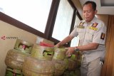 Petugas kepolisian memeriksa tabung gas subsidi tiga kilogram yang berhasil diamankan dari tersangka pengepul ilegal saat rilis kasus di Mapolresta Pontianak, Kalimantan Barat, Kamis (20/12/2018). Satreskrim Polresta Pontianak menangkap pengepul gas elpiji subsidi ilegal yaitu YSA (35) yang telah menjual 40-100 tabung gas subsidi per minggu seharga Rp19 ribu per tabung ke warung dan toko kelontong selama delapan bulan terakhir. ANTARA FOTO/Jessica Helena Wuysang