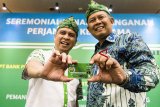 Managing Director Grab Indonesia Ridzki Kramadibrata (kiri) bersama Senior Executive Vice Presiden Komersial dan UMKM Bank BJB Beny Riswandi (kanan) menunjukan kartu ATM berupa identitias atau kartu anggota co-branding Bank BJB Grab Indonesia di sela-sela perjanjian kerjasama di Bandung, Jawa Barat, Senin (17/12/2018). Perjanjian kerjasama Bank BJB dengan Grab Indonesia dalam rangka memudahkan para mitra pengemudi Grab dalam bertransaksi perbankan, meningkatkan jumlah nasabah baru dan memudahkan pembayaran pajak kendaraan bermotor yang bisa dicicil (T-Samsat). ANTARA JABAR/M Agung Rajasa/agr. 