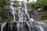 Pengunjung berfoto di kawasan wisata alam Curug Luhur Cigangsa, Surade, Kabupaten Sukabumi, Jawa Barat, Selasa (12/12/2018). Curug Luhur Cigangsa yang memiliki tinggi 50 meter serta menawarkan pemandangan alam dan suasana air terjun yang masih alami tersebut menjadi salah satu alternatif wisata liburan favorit bersama keluarga. ANTARA JABAR/Nurul Ramadhan/agr. 