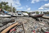 Warga melintas di antara kapal yang terdampar ke pemukiman penduduk akibat gelombang tsunami di desa Sukamanah, Anyer, Banten, Senin (24/12/2018). Tsunami yang terjadi pada Sabtu (22/12) mengakibatkan sejumlah rumah mengalami rusak berat karena tertabrak kapal serta terendam lumpur. ANTARA FOTO/Muhammad Adimaja/nym.