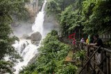 Pengunjung menikmati air terjun di kawasan wisata alam Geopark Curug Cimarinjung, Ciemas, Kabupaten Sukabumi, Jawa Barat, Minggu (16/12/2018). Curug Cimarinjung yang menawarkan pemandangan alam serta suasana deburan air terjun yang masih alami tersebut menjadi salah satu alternatif destinasi wisata liburan favorit bersama keluarga di akhir pekan. ANTARA JABAR/Nurul Ramadhan/agr. 