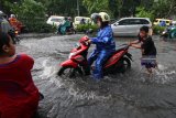 Sejumlah anak membantu warga mendorong motornya yang mogok di Jalan Ngagel Jaya Selatan, Surabaya, Jawa Timur, Sabtu (19/1/2019). Hujan deras selama sekitar empat jam yang mengguyur kota Surabaya menyebabkan sejumlah kawasan di kota Surabaya tergenang air. Antara Jatim/Didik Suhartono/ZK.