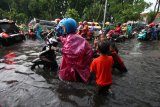 Sejumlah anak membantu warga mendorong motornya yang mogok di Jalan Ngagel Jaya Selatan, Surabaya, Jawa Timur, Sabtu (19/1/2019). Hujan deras selama sekitar empat jam yang mengguyur kota Surabaya menyebabkan sejumlah kawasan di kota Surabaya tergenang air. Antara Jatim/Didik Suhartono/ZK.