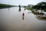 Warga melintas di Jalan Raya yang terendam banjir di Porong, Sidoarjo, Jawa Timur, Sabtu (19/1/2019). Banjir yang diakibatkan curah hujan tinggi sejak Jumat (18/1) malam tersebut mengakibatkan jalan raya Porong terendam air setinggi 70 cm. Antara Jatim/Umarul Faruq/ZK.