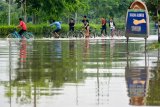 Sejumlah anak melintas di Jalan Raya yang terendam banjir di Porong, Sidoarjo, Jawa Timur, Sabtu (19/1/2019). Banjir yang diakibatkan curah hujan tinggi sejak Jumat (18/1) malam tersebut mengakibatkan jalan raya Porong terendam air setinggi 70 cm. Antara Jatim/Umarul Faruq/ZK.