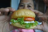 Pembuat kue memperlihatkan burger inovasi berbahan ikan lele (clarias) di industri rumahan Aneka Olahan Lele Matrix, Sumbersari, Jember, Jawa Timur, Selasa (15/1/2019). Ikan lele merupakan ikan air tawar yang kaya gizi dan dagingnya bisa diolah menjadi aneka makanan termasuk dibuat daging pengisi burger (patty) sebagai pengganti daging sapi.  Antara Jatim/Seno/ZK.