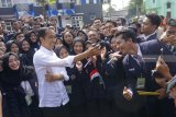 Presiden RI Joko Widodo (tengah) menyempatkan berswafoto dan membuat video story (vlog) bersama para mahasiswa usai meresmikan 3 unit rusunawa di halaman kampus STKIP Tulungagung, Jawa Timur, Jumat (4/1). Presiden Jokowi mengatakan, selama kurun 2018 pemerintah telah membangun 300 rumah susun (rusun) dengan 45 di antaranya berada di Jawa Timur, terbanyak dibanding daerah-daerah lain. Antara Jatim/Destyan Sujarwoko/ZK.