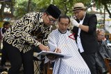 Presiden Joko Widodo (tengah) berbincang dengan Gubernur Jawa Barat Ridwan Kamil (kiri) disela-sela mengikuti potong rambut massal di area wisata Situ Bagendit, Garut, Jawa Barat, Sabtu (19/1/2019). ANTARA JABAR/Puspa Perwitasari/agr. 