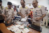 Kepala Divisi keimigrasian Kementerian Hukum dan Ham Jawa Barat Arif Budijanto (tengah) menunjukan barang bukti berupa paspor yang telah dirobek dari Warga Negara Asing (WNA) saat gelar perkara di Kantor Imigrasi Kelas I Bandung, Jawa Barat, Rabu (2/1/2019). Kementerian Hukum dan HAM Wilayah Jawa Barat bersama Poltabes Bandung, dan BAIS TNI mengamankan delapan orang WNA asal Nigeria terkait pelanggaran izin tinggal di Indonesia yang melanggar pasal 71 huruf b Undang-undang no. 6 tahun 2011 tentang keimigrasian. ANTARA JABAR/Raisan Al Farisi/agr. 