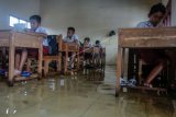 Sejumlah siswa mengikuti latihan pra ujian (try out) dengan kondisi ruang kelas tergenang banjir di Madrasah Ibtidaiyah Salafiyah, Desa Tegaldowo, Tirto, Kabupaten Pekalongan, Jawa Tengah, Selasa (29/1/2019). Sebanyak 16 siswa dari 94 siswa tetap mengikuti latihan pra ujian dari Senin (28/1) hingga Rabu (30/1) dengan kondisi sekolah terdampak banjir setinggi sekitar 50 centimeter. ANTARA FOTO/Harviyan Perdana Putra/nym