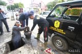 Petugas dari dinas PUPR Kota Banjarmasin sedang membersihkan drainase di jalan Lambung Mangkurat, Banjarmasin, Rabu (02/19). Dalam beberapa hari ini insensitas hujan di kota Banjarmasin cukup tinggi mengakibatkan sejumlah drainase tak dapat menampung debit air. Foto: Antaranews Kalsel/Bayu Prata,a/f