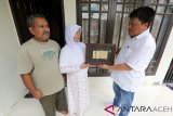 General Manager PT Garuda Indonesia Aceh Endy Latief (kanan) menyerahkan kertas obligasi yang telah dibingkai sebagai upaya perawatan naskah sejarah kepada Erlina Mutia (dua kiri) di Desa Ilie Ulee Kareng, Banda Aceh, Aceh, Sabtu (9/2/2019). Obligasi milik alrmarhum M Hasan orang tua dari Erlina Mutia merupakan bukti sumbangan yang diserahkan kepada Pemerintah tanggal 28 Agustus 1950 di Kabupaten Pidie untuk pembelian pesawat RI-001 Seulawah yang merupakan cikal bakal Indonesian Airways. (Antara Aceh/Irwansyah Putra)