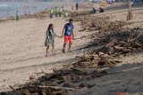 Wisatawan melintas di dekat sampah yang terdampar akibat cuaca buruk di Pantai Kuta, Badung, Bali, Senin (11/2/2019). Hujan deras disertai angin kencang yang melanda Bali berdampak pada arus laut yang terus membawa sampah dari daerah lain dan terdampar sejumlah pantai bagian selatan Bali. (ANTARA FOTO)