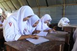  Siswa Madrasah Tsanawiyah (MTs) Fathur Rahman belajar di tenda darurat di Desa Sukorambi, Sukorambi, Jember, Jawa Timur, Selasa (12/2/2019). Sejumlah siswa MTs tersebut terpaksa belajar di tenda darurat karena ruang kelas mereka ambruk akibat hujan deras dan angin kencang. Antara Jatim/Seno/zk