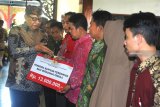 Menteri Koperasi dan UKM,Â Anak Agung Gede Ngurah Puspayoga (kiri) menyerahkan bantuan bagi wirausaha pemula di Pendopo Kabupaten Pamekasan, Jawa Timur, Jumat (15/2/2019). Sinergi pemberdayaan Koperasi dan UKM dengan pemkab tersebut meliputi pelatihan kewirausahaan, pelatihan vocational, pelatihan perkoperasian, sosialisasi dan Bimtek dana bergulir LPDB-KUMKM serta Penyerahan Program Strategis Kemenkop dan UKM. Antara Jatim/Saiful Bahri/ZK.