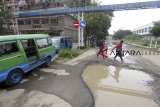 Penumpang melewati kubangan air jalan rusak di Terminal Bubulak, Kota Bogor, Jawa Barat, Jumat  (15/2/2019). Dinas Perhubungan Kota Bogor akan menyiapkan anggaran sebesar Rp700 juta untuk revitalisasi dan perbaikan fisik infrastruktur terminal  Bubulak. ANTARA JABAR/Yulius Satria Wijaya/agr. 