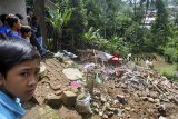 Sejumlah anak melihat lokasi longsor di RT 02/05 Kampung Ciapus Permeha, Desa Sukamakmur, Kecamatan Ciomas, Kabupaten Bogor, Jawa Barat, Sabtu (16/2/2019). Hujan deras yang terus mengguyur wilayah Desa Sukamakmur pada Jum'at (15/2/2019) malam menyebabkan pondasi Tembok Pembatas Tebing (TPT) setinggi lima meter ambruk dan menimpa rumah dibawahnya sehingga empat warga tewas yang merupakan satu keluarga dan lima warga lainnya luka-luka dibawa ke rumah sakit. ANTARA JABAR/Arif Firmansyah/agr.