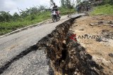 Sepeda motor melintas di jalan yang terbelah akibat pergerakan tanah di jalur wisata, Karang Tengah, Sentul,  Kabupaten Bogor, Jawa Barat, Sabtu (16/2/2019).  Pergerakan tanah disebabkan oleh tingginya intesitas hujan di kawasan tersebut, mengakibatkan akses jalan menuju tempat wisata tidak bisa dilantasi oleh kendaraan roda empat karena berbahaya. ANTARA JABAR/Yulius Satria Wijaya/agr.