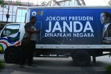 Warga melintas di samping mobil box yang menjadi media alat peraga kampanye (APK) bergambar calon presiden petahana Joko Widodo yang terparkir di sebuah pusat perbelanjaan di kawasan Serpong, Tangerang, Banten, Minggu (17/2/2019). Menurut sopir yang membawa mobil tersebut, setiap harinya APK mobil ini berkeliling di jalan-jalan kawasan Tangerang dan berhenti di setiap pusat perbelanjaan. (ANTARA FOTO)