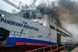 Asap membubung dari dalam KMP Panorama Nusantara yang terbakar di galangan PT Janata Marina Indah Nusantara, Tanjung Emas, Semarang, Jawa Tengah, Senin (18/2/2019). Belum diketahui penyebab, korban jiwa, dan kerugian atas terbakarnya kapal penumpang yang sedang dalam proses perbaikan di galangan tersebut, sebanyak enam unit mobil pemadam kebakaran serta dua kapal pemadam dikerahkan untuk memadamkan api. (ANTARA FOTO)