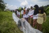 Seorang seniman asal Padang melakukan aksi teatrikal terkubur oleh sampah plastik di sekitaran lokasi longsornya sampah TPA Leuwigajah, Cimahi, Jawa Barat, Kamis (21/2/2019). Aksi tabur bunga serta teatrikal tersebut dilakukan dalam rangan memperingati Hari Sampah Nasional dan 14 tahun tragedi longsornya sampah di TPA Leuwigajah yang menewaskan 157 orang. ANTARA JABAR/Raisan Al Farisi/agr.