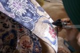 Perajin menggoreskan malam atau tinta pewarna ke permukaan kain yang telah diberi motif di sentra kerajinan batik tulis Omah Gajah di Tulungagung, Jawa Timur, Minggu (24/2/2019). Perajin batik tulis setempat mengeluhkan sulitnya mencari tenaga pembantu pembatik tangan sebagai dampak modernisasi alat serta rendahnya minat generasi muda terhadap aktivitas batik tulis. Antara Jatim/Destyan Sujarwoko/ZK.