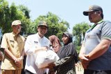 Wakil Gubernur Jawa Timur Emil Elestianto Dardak (kedua kiri) didampingi Bupati Magetan Suprawoto (kiri) menyerahkan bantuan bahan pokok kepada warga seusai upacara Pembukaan TNI Manunggal Membangun Desa (TMMD) ke-104 tahun 2019 di lapangan Desa Poncol, Kabupaten Magetan, Jawa Timur, Selasa (26/2/2019). TMMD ke-104 akan berlangsung selama 30 hari mulai 26 Februari hingga 27 Maret 2019. Antara Jatim/Siswowidodo/ZK.