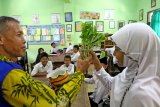 Petugas puskesmas menunjukan pas bunga yang menjadi tempat sarang nyamuk saat memberikan edukasi mengenai bahaya Demam Bersarah (DBD) kepada siswa Sekolah Dasar di Banyuwangi, Jawa Timur, Jumat (1/2/2019). Sosialisasi oleh Juru Pemantau Jentik (Jumantik) kepada masyarakat dan siswa tersebut, sebagai upaya memberikan edukasi untuk mencegah peredaran penyakit DBD. Antara Jatim/Budi Candra Setya/Zk