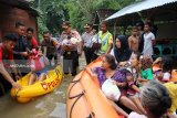 Kapolres Bojonegoro AKPB Ary Fadli (tengah) membobong bayidalam evakuasi sejumlah warga korban banjir di Desa Sukorejo, Kecamatan Kota, Rabu (6/3). Dalam proses evakuasi dengan memanfaatkan perahu karet itu, ada10 warga terdiri dari orang tua, orang sakit, ibu hamil dan anak-anak di evakuasi ke tempat yang aman, ratusan warga lainnya masih bertahan di rumahnya yang dikepung air banjir. Antarajatim/Slamet Agus Sudarmojo/19. 