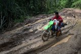 Seorang tukang ojek berusaha melewati jalan berlumpur menuju daerah terpencil Kecamatan Pinogu, Kabupaten Bone Bolango, Gorontalo, Sabtu (9/3/2019). Dengan kondisi jalan yang belum seluruhnya dibeton, berlumpur dan jarak yang jauh, biaya naik ojek Pinogu dari Kecamatan Suwawa Timur atau wilayah terdekat dengan ibukota kabupaten, bervariasi mulai Rp500 ribu hingga Rp1 juta untuk pulang pergi. (ANTARA FOTO)