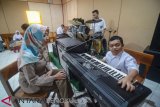 Seorang guru mengawasi siswa difabel yang tengah melaksanakan ujian praktik musik modern di SLBN A Kota Bandung, Jawa Barat, Selasa (12/3/2019). SLBN Negeri A Kota Bandung menggelar ujian praktik keterampilan pilihan dalan rangka USBN tahun ajaran 2018-2019 yang dilaksanakan hingga 15 Maret mendatang. (ANTARA FOTO)