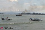 Para nelayan tradisional di Kelurahan Malabero Kota Bengkulu menahan dan membakar satu unit kapal pengguna alat tangkap pukat harimau atau trawl di tengah perairan sekitar Malabero, Kamis (14/3). Para nelayan Malabero membawa sekitar 20 kapal yang masing-masing kapal berisikan 5 hingga 15 orang anak buah kapal (ABK) berlayar menuju Pulau Baai untuk menghadang kapal trawl tersebut. (Foto Antarabengkulu.com)