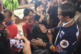 Seorang wanita menangis ketika menyampaikan keluhannya kepada Presiden Joko Widodo (kanan) saat kunjungan ke Pasar Petisah di Medan, Sumatera Utara, Sabtu (16/3/2019). Dalam kunjungannya presiden mendengarkan keluhan-keluhan masyarakat secara langsung. ANTARA FOTO/Akbar Nugroho Gumay/nz