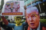 Massa yang tergabung dalam Komite Solidaritas Untuk Venezuela (KSV) menggunakan topeng Presiden Amerika Serikat Donald Trump saat melakukan aksi teaterikal di Jalan Asia Afrika, Bandung, Jawa Barat, Senin (18/3/2019). Dalam aksi tersebut, mereka menyatakan untuk menentang intervensi imperialisme Amerika Serikat di Venezuela serta menuntut agar Amerika Serikat untuk menghentikan blokade dan perang ekonomi di Venezuela. ANTARA JABAR/Raisan Al Farisi/agr