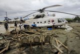 Sejumlah warga berada di dekat helikopter yang bergeser dari tempatnya akibat banjir bandang di Sentani, Kabupaten Jayapura, Papua, Minggu (17/3/2019). (Antara FOTO)