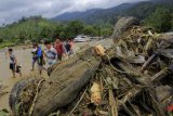 Sejumlah warga melintasi sebuah mobil yang terbalik akibat banjir bandang di Sentani, Kabupaten Jayapura, Papua, Minggu (17/3/2019). (ANTARA FOTO)