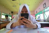 Seorang siswa menggunakan Smartphone Android saat mengerjakan soal UASBN 2019 di MAN 2 Model Banjarmasin, Kalimantan Selatan, Rabu (20/3/2019).MAN 2 Model Banjarmasin mulai menerapkan penggunaan teknologi smart router dalam pelaksanaan UASBN sehingga mempermudah para siswa siswi dalam mengerjakan soal ujian berbasis komputer karena dapat menggunakan Smartphone pribadi.Foto Antaranews Kalsel/Bayu Pratama S.